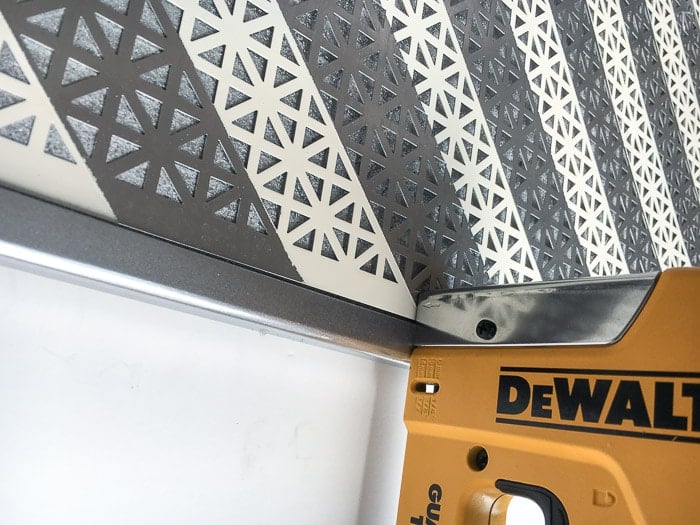 Attaching the metal sheet to corkboard for a DIY Jewelry Organizer using a staple gun
