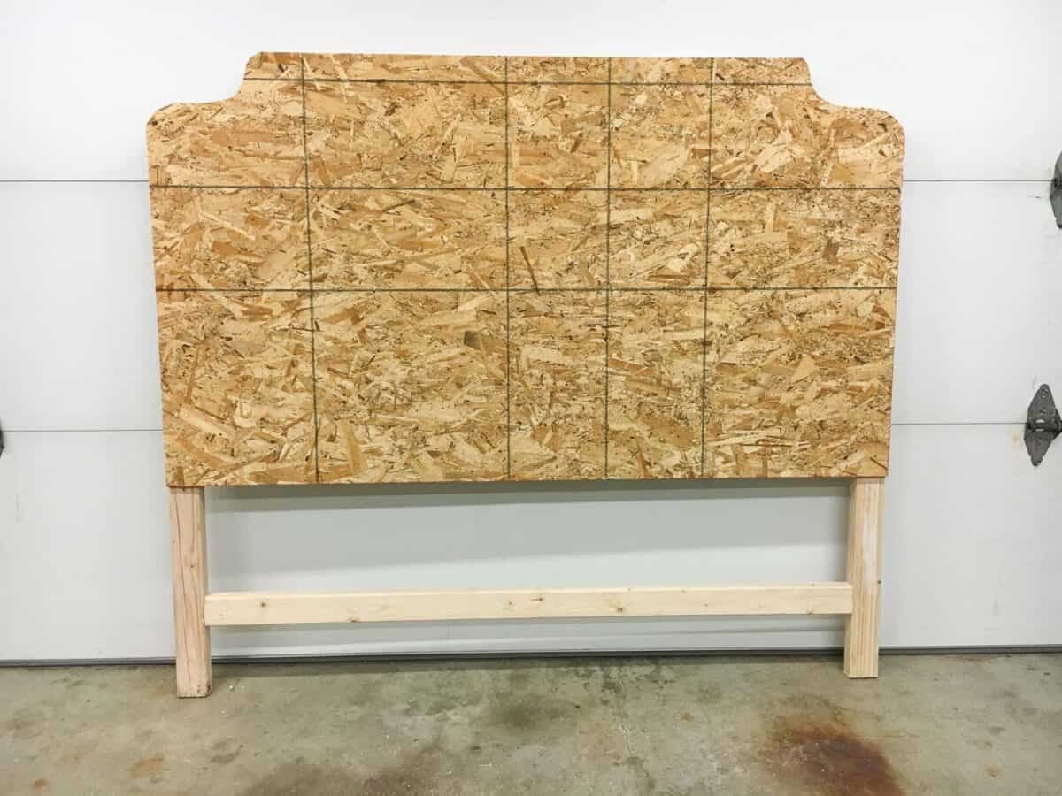 Front view of the headboard against the garage door. The plywood is visible with the 2x4 frame on the back.