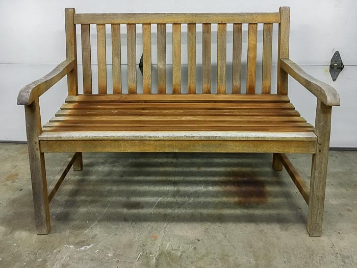 Old beaten up wooden patio bench in garage