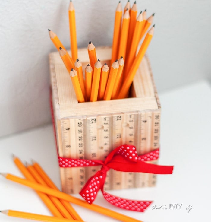 DIY pencil holder made from scrap wood and rulers on table with yellow pencils