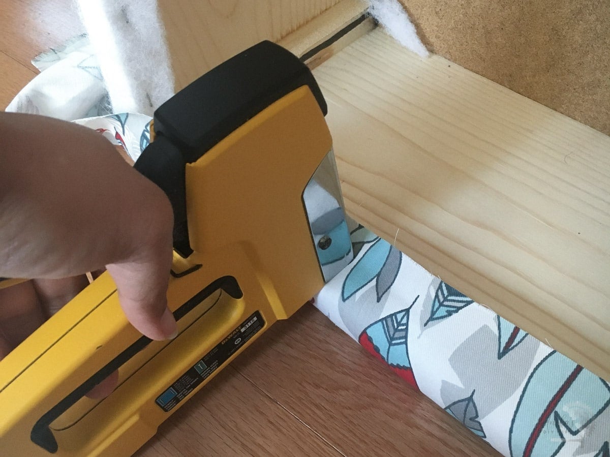 woman stapling the fabric to the ottoman