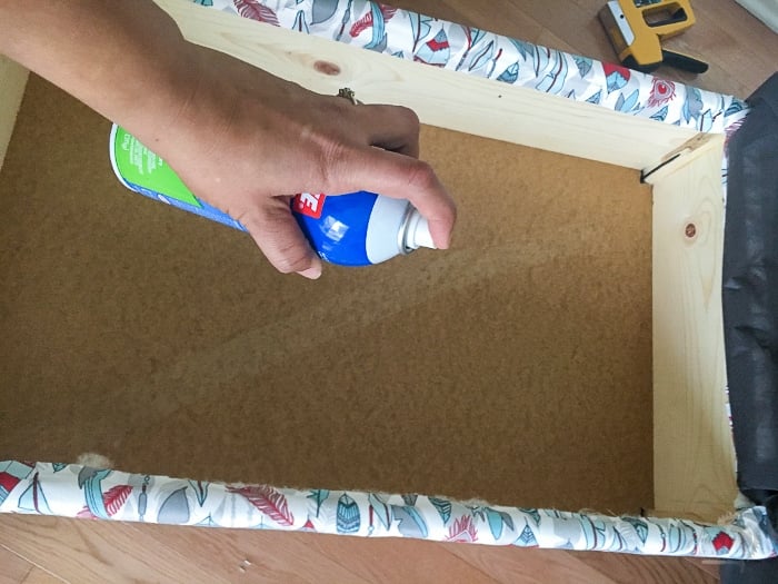 applying spray adhesive to inside of ottoman