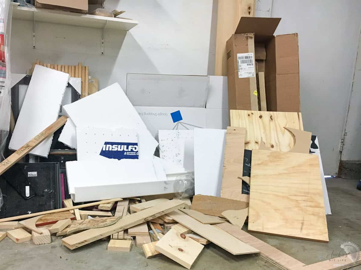 Pile of random wood boards, styrofoam and photo frames on the garage floor.