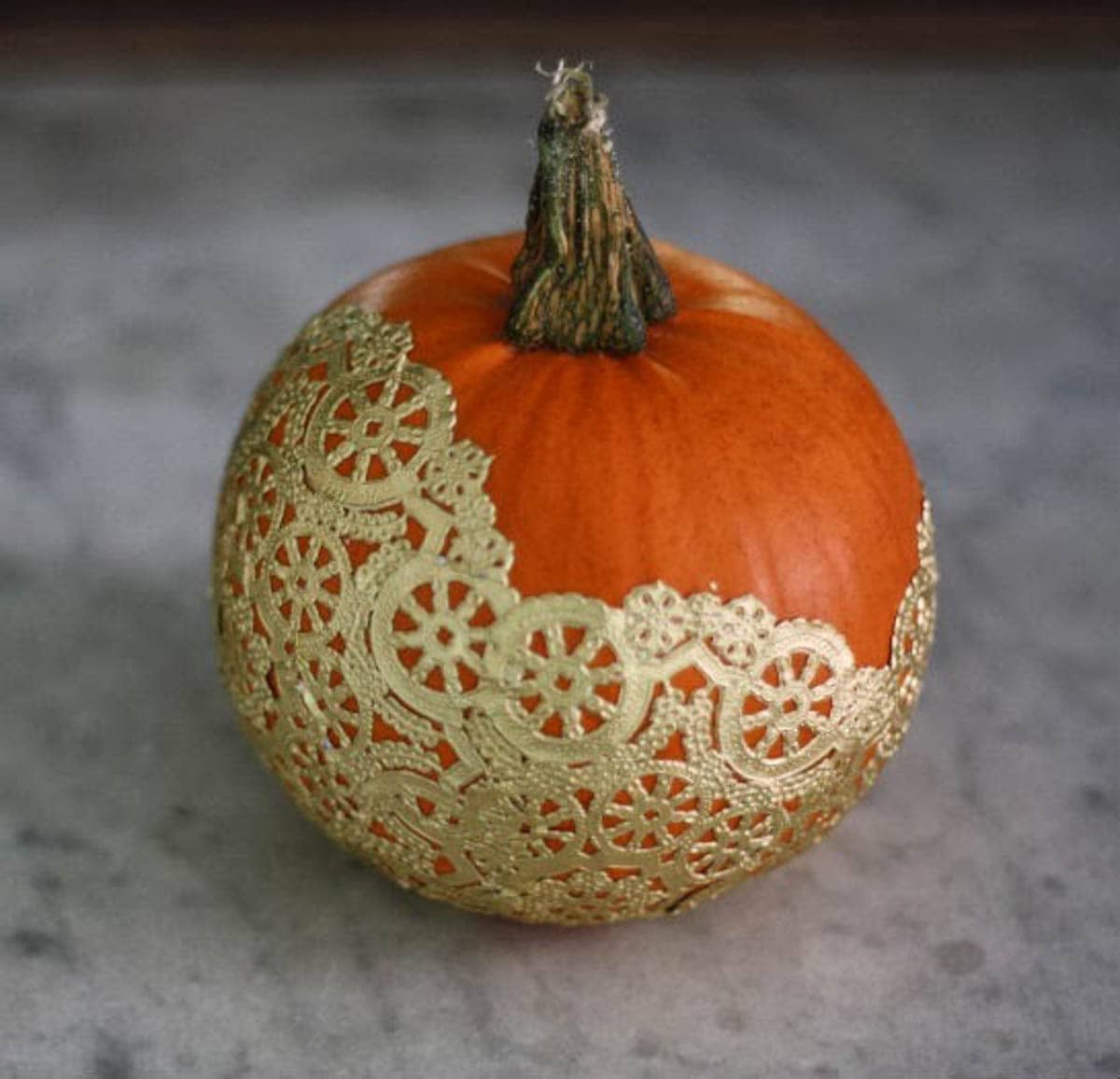 gold painted doily on an orange pumpkin