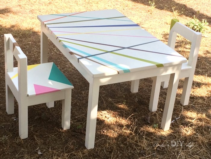 White DIY kids table and chair with colorful stripes in back yard