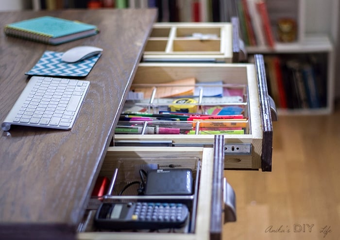 Drawers inside the desk with organized pens and markers