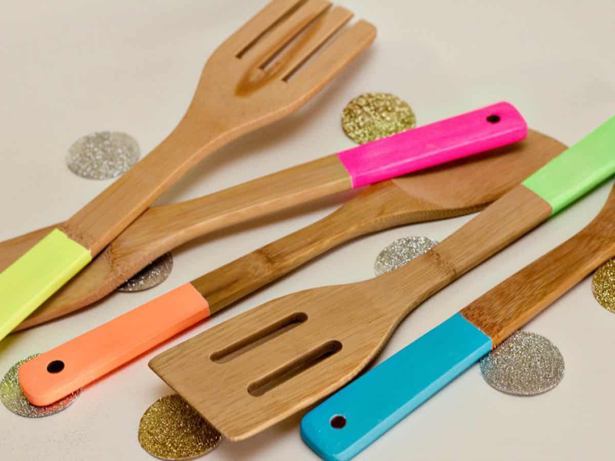 Wooden cooking utensils with handles painted in neon pink, orange, blue, and yellow