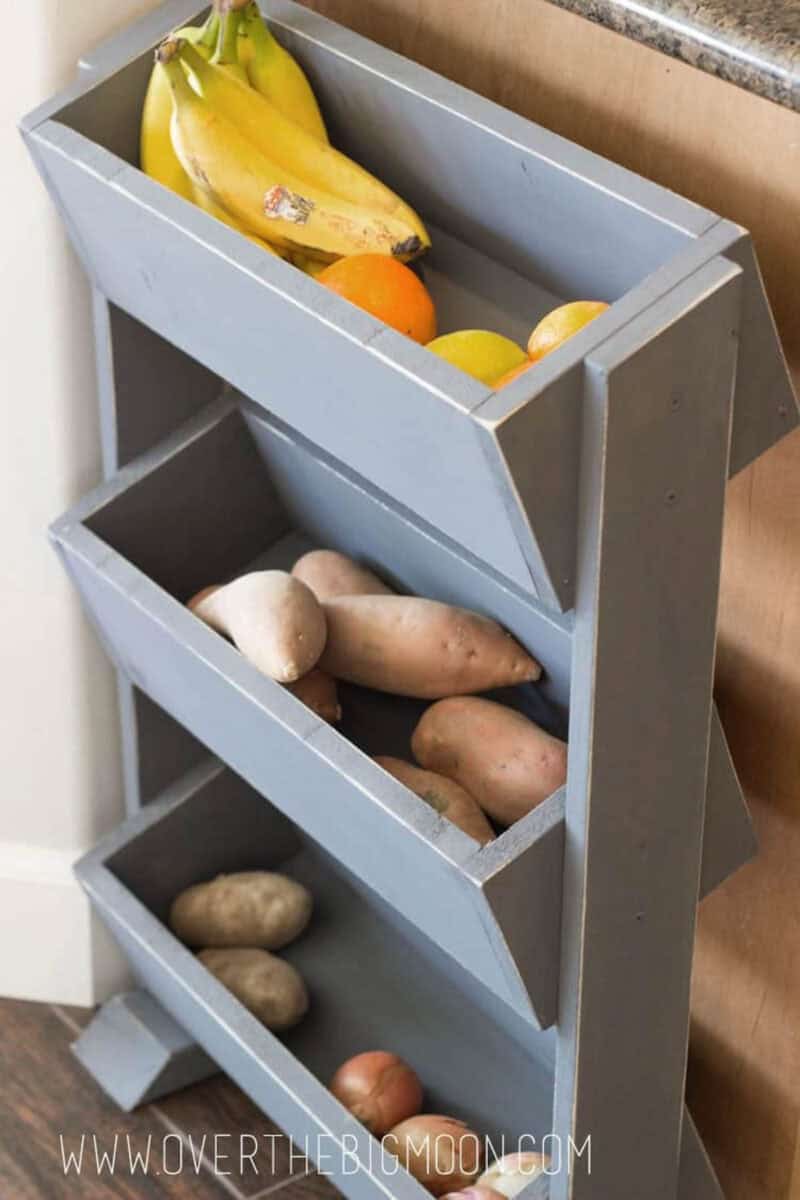 DIY produce bin painted gray next to a kitchen cabinet