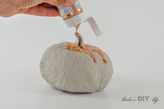 pouring paint over DIY concrete pumpkins