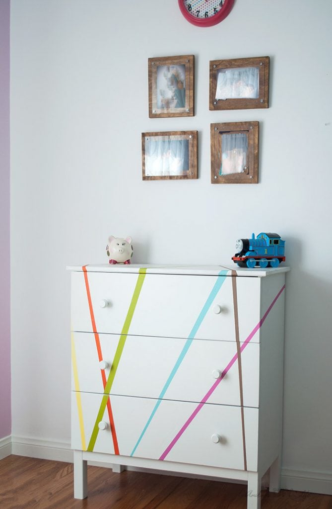 Colorful dresser in kids room with picture frames on top.