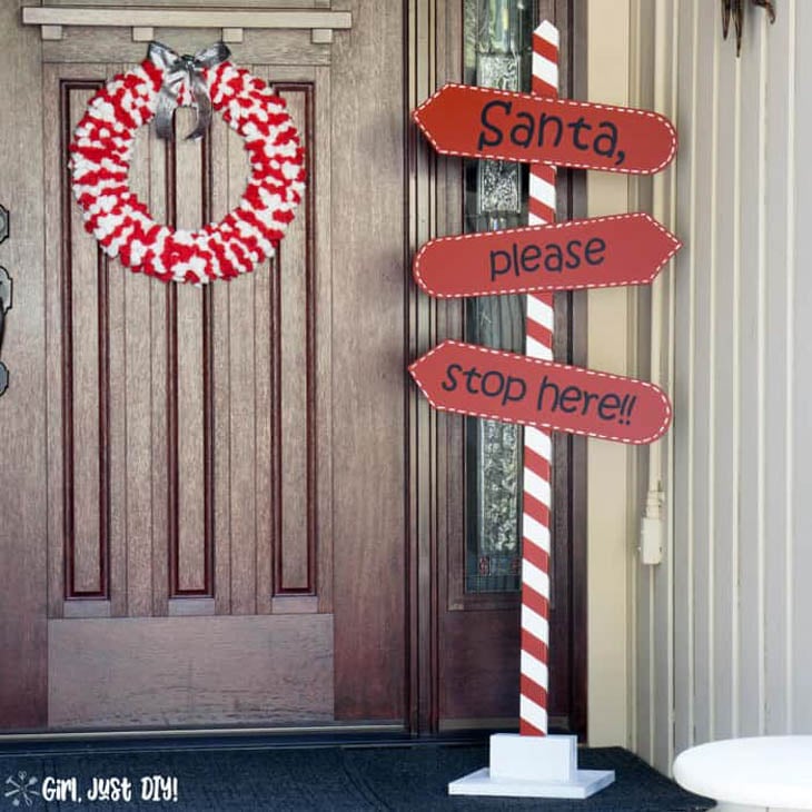 Red and white striped Santa Please Stop Here wood pole with directional arrows