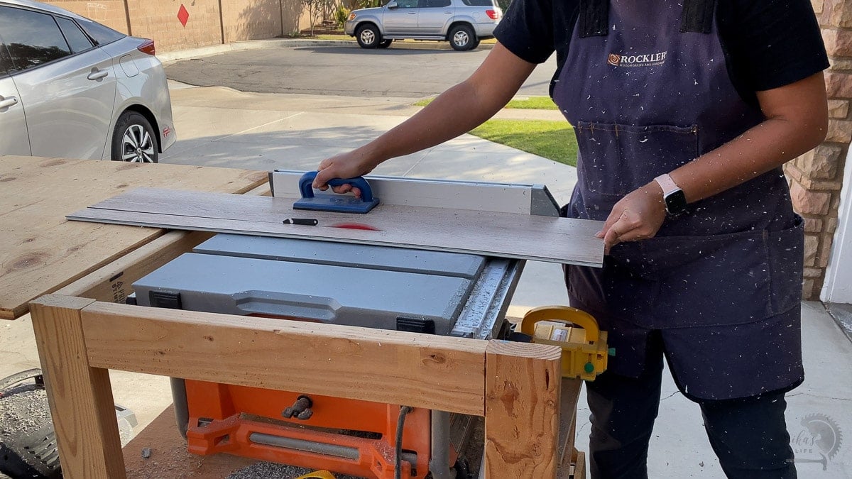 woman cutting down flooring plank with table saw