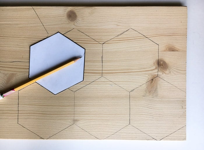 Drawing hexagons on scrap wood for the DIY hexagonal marble and gold coasters using a paper template