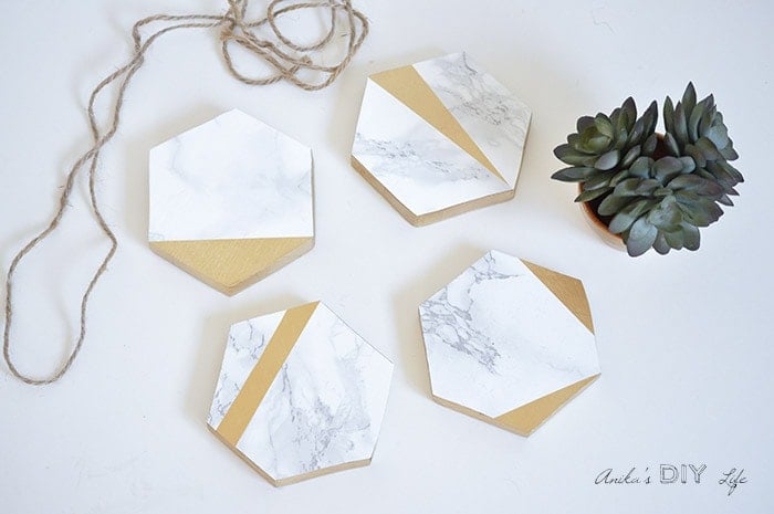 Four DIY Hexagonal marble and gold coasters on white background with twine.