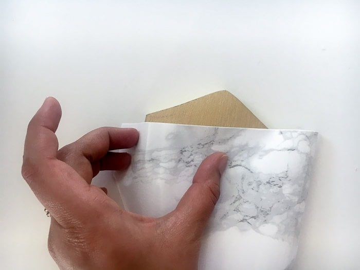 Applying marble contact paper to the DIY hexagonal marble and gold coasters