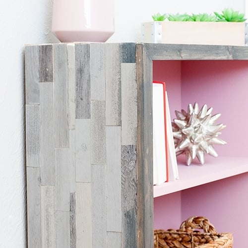 A DIY rustic modern weathered barn wood bookshelf that is super easy to make! No barn wood used in this project! See how to makeover a laminate oak bookshelf with this tutorial on how to paint laminate furniture easily with minimum prep and add a touch of rustic-modern with peel and stick barn wood tile.
