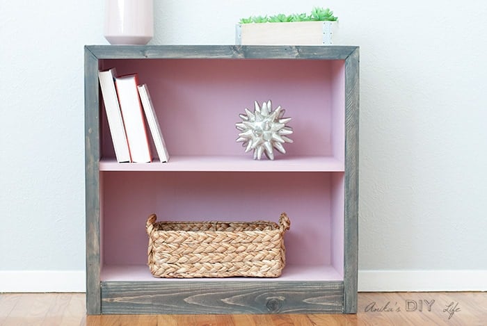 Pink and grey laminate bookshelf makeover - the after. Interior is pink and the outside with grey peel and stick barn wood tile.