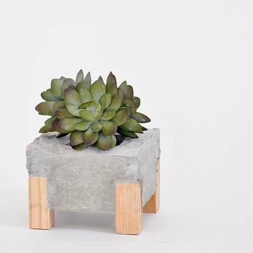 How to make a DIY Concrete Planter with Wooden accents. This DIY concrete and wood planter is easy to make and creates a gorgeous concrete planter with an unexpected twist.