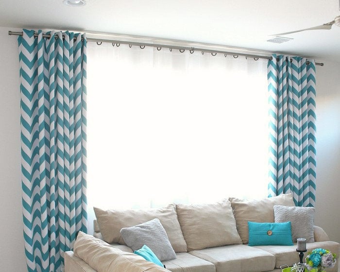 DIY curtain rod using electrical conduit in living room with teal and white curtains