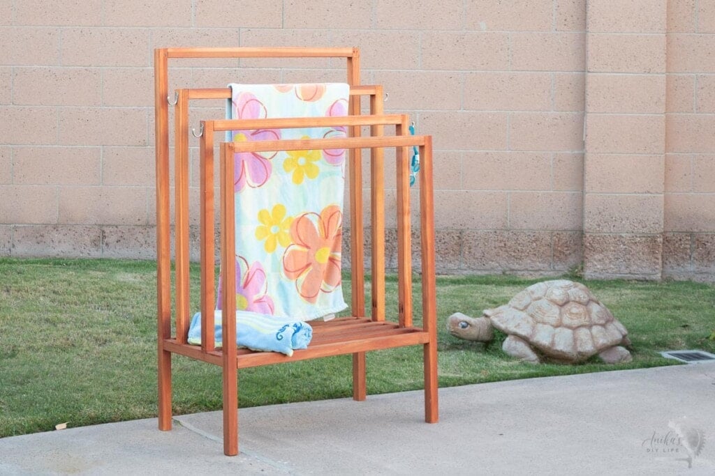 Redwood towel rack in backyard with colorful towel on it.