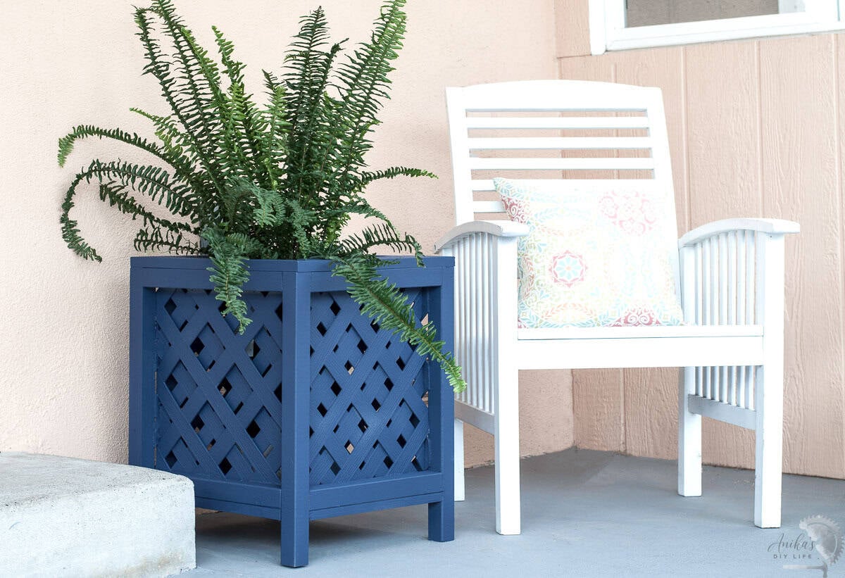 navy blue lattice planter with ferns in patio next to white chair