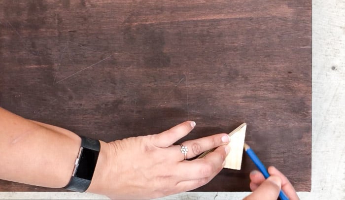 Tracing pattern on plywood using a scrap wood triangle for DIY wood wall art