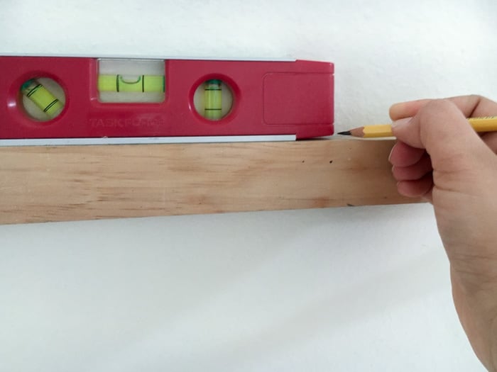 Marking spots for rain gutter bookshelf hangers using a level.