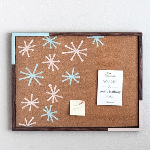 Make a gorgeous DIY cork bulletin board with a roll of cork and scrap wood with this full tutorial with pictures. This easy stenciled cork board adds fun, color, and function to any room!