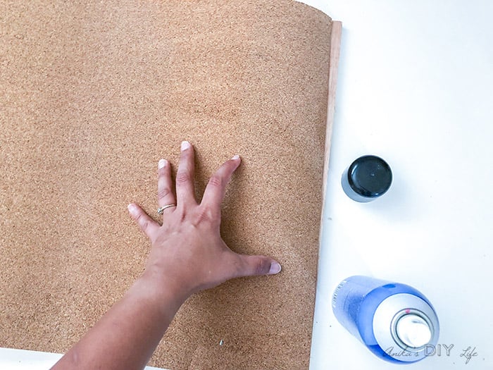 Attaching corkboard roll to plywood using spray adhesive for a DIY cork bulletin board