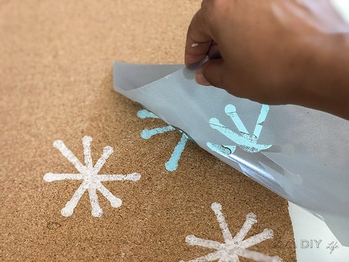 Peeling off stencil from the DIY cork bulletin board