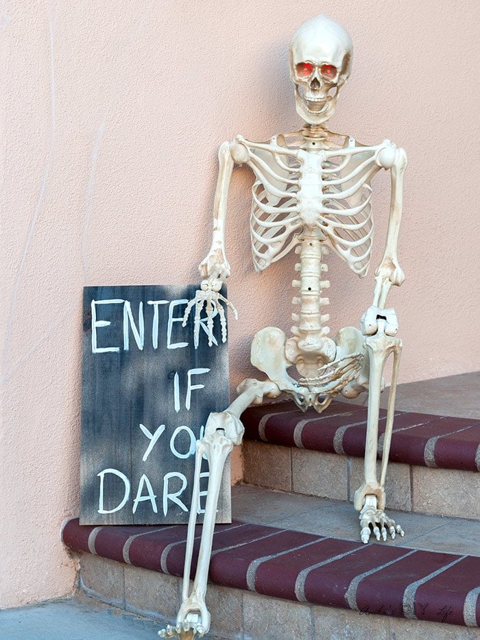 Front porch halloween decoration idea for this year with skeleton sitting with sign
