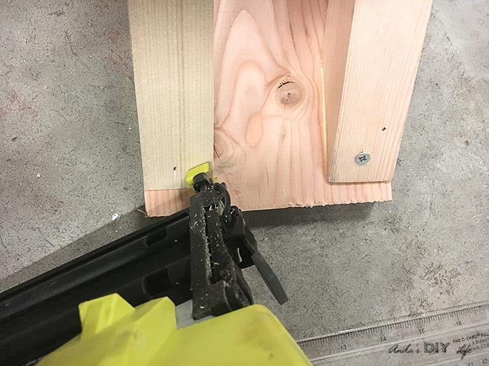 attaching the front board of the tiered DIY plant stand to the legs
