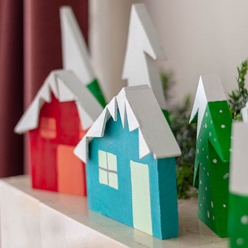 See how you can make a DIY Christmas village using scrap wood. This bright and happy Christmas village display is an easy project!