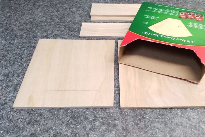 5 cut plywood pieces on counter with cardboard box.