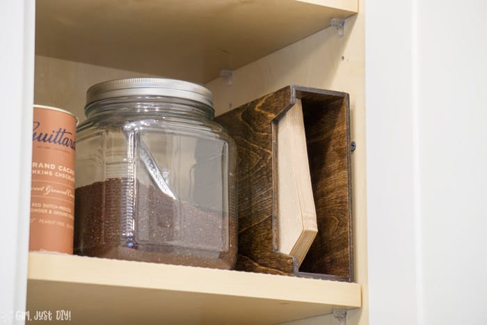 Coffee filter holder in cabinet next to canister.