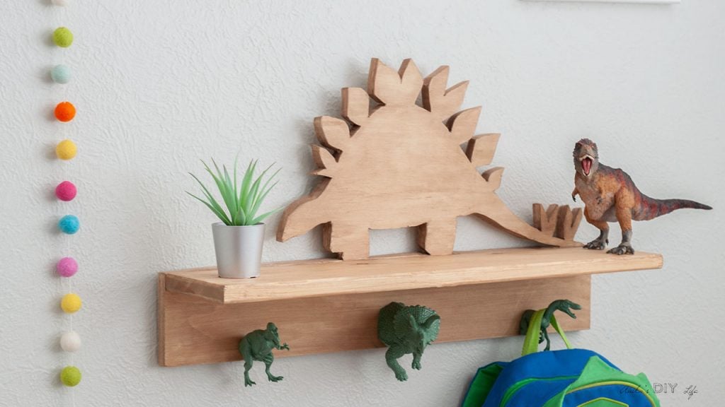 DIY Dinosaur shelf with dinosaur hooks on the wall with backpack hanging