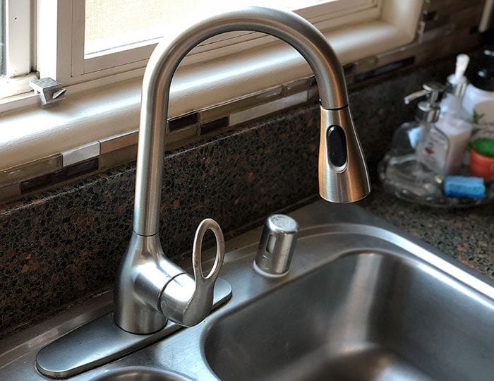 Old faucet in kitchen sink before replacing the faucet