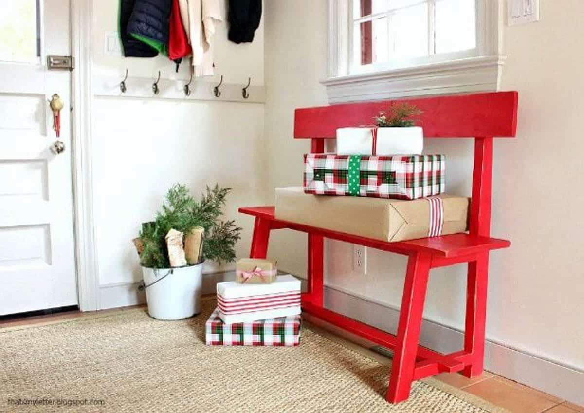 Red entryway bench made with wood with presents on the floor and bench seat