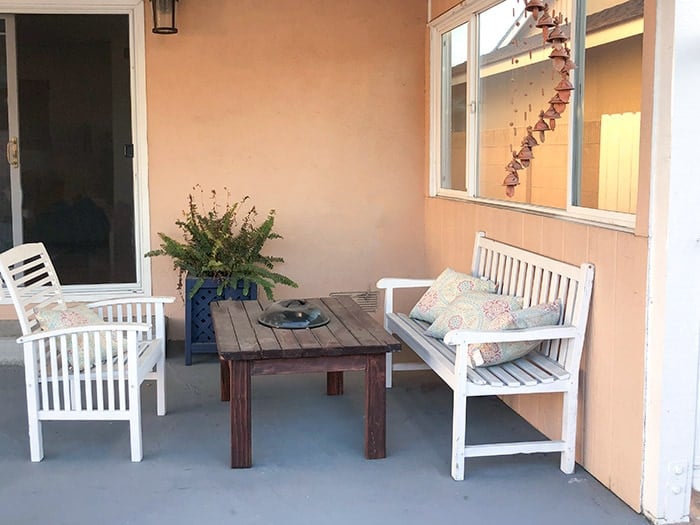 Bare patio before the makeover with 2 white chairs and an old grill table