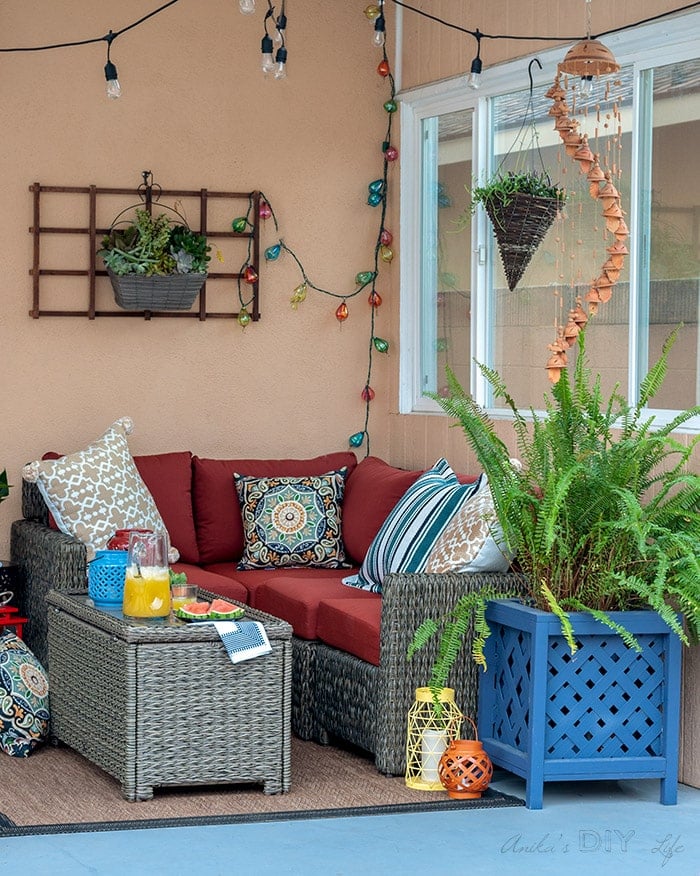 Full view of small patio decorating ideas - red sectional, blue planter and lights