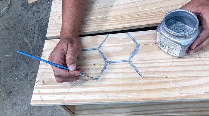 Applying silver paint to engraved lines.