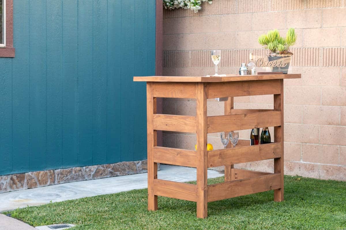 Homemade wooden outdoor bar in backyard with drinks on it