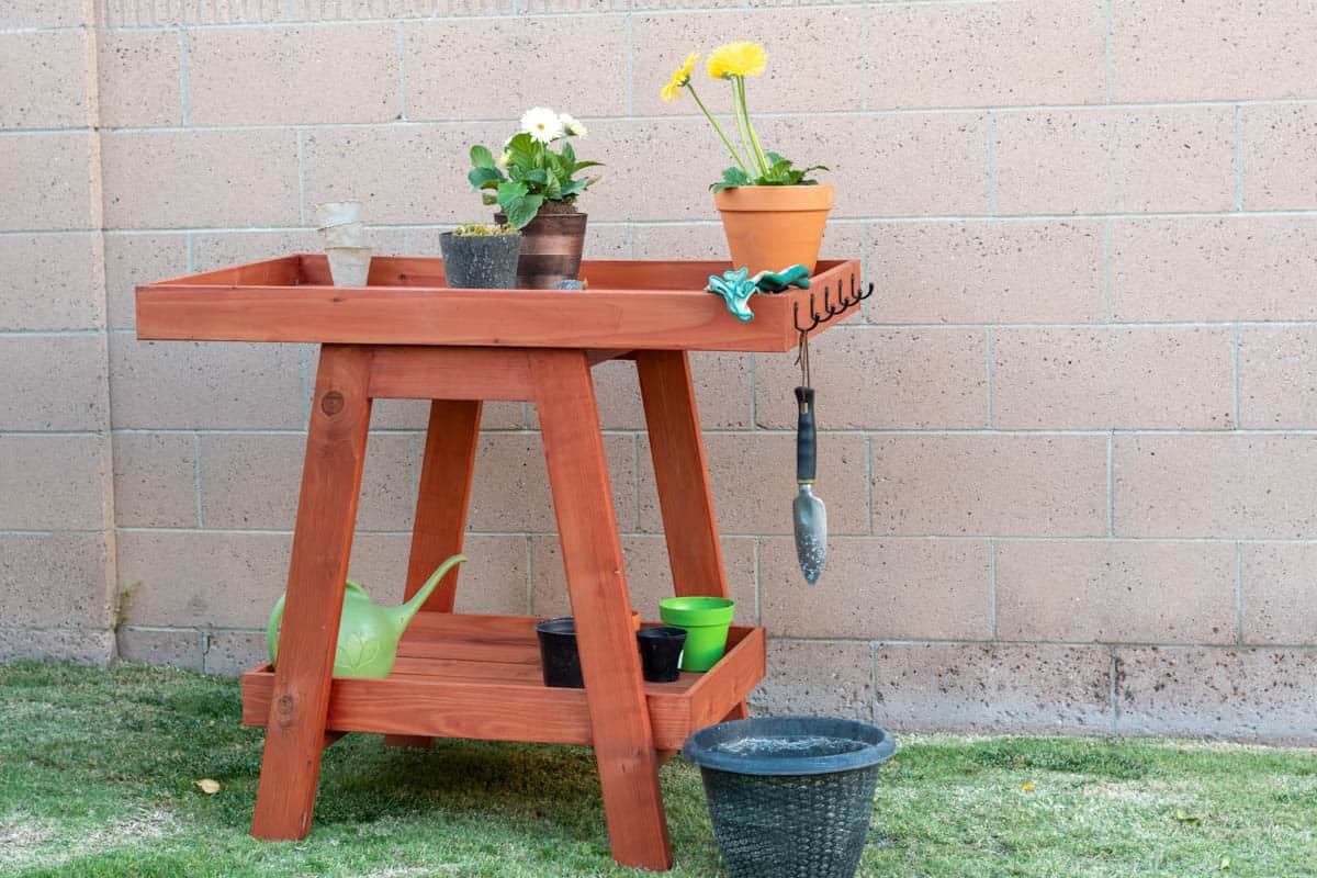 Potting bench with plants and potting tools sitting in the grass