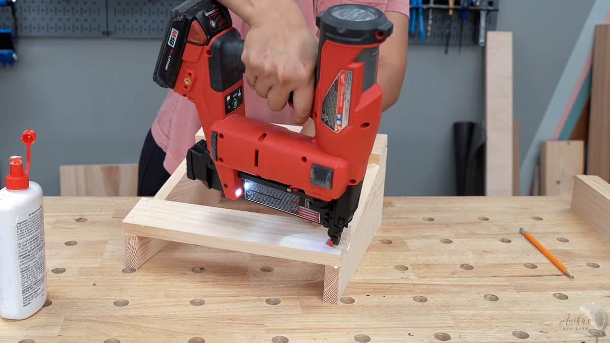 Attaching the bottom slat of the wooden foot rest using a nail gun