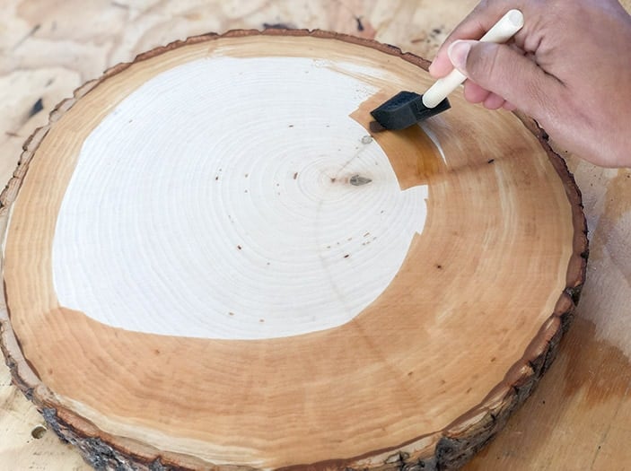 applying finish to the wood slice with foam brush
