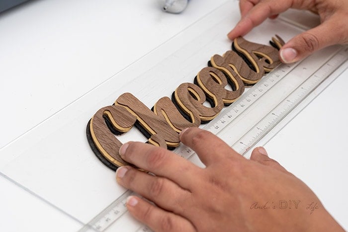 Attaching word onto plexiglas.