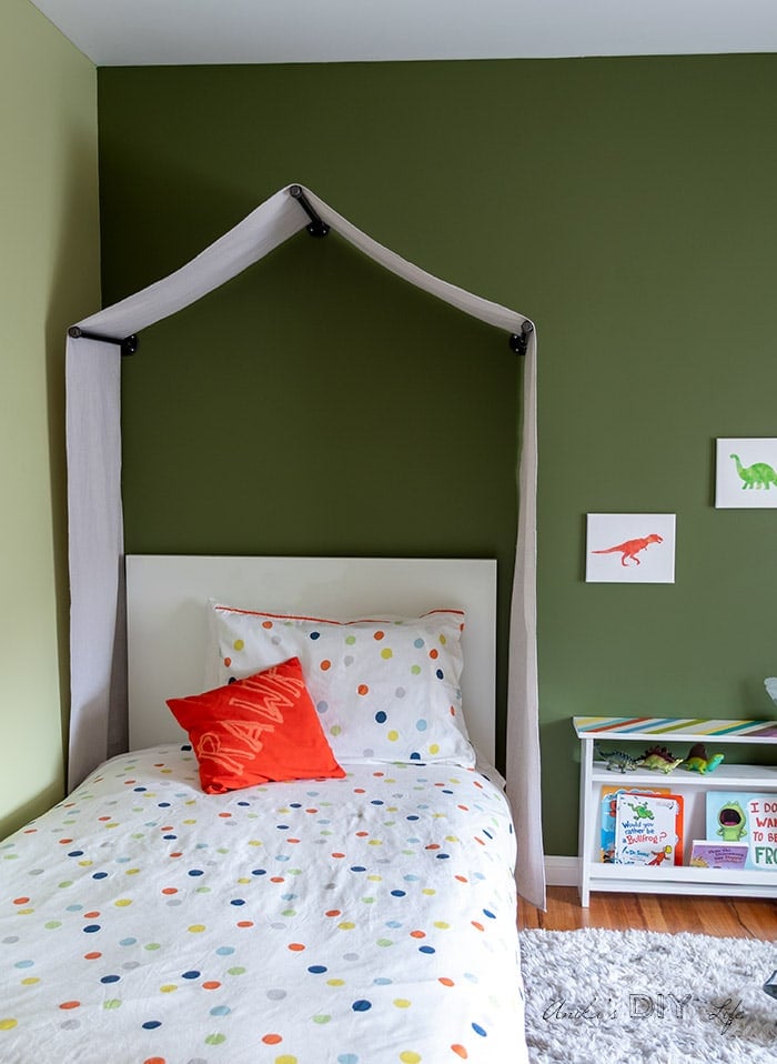 Toddler room painted dark green with tent canopy and dinosaur theme