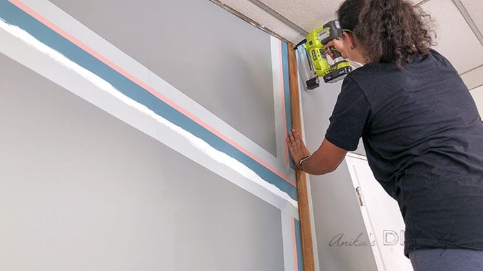 Woman attaching wood board to wall for accent wall