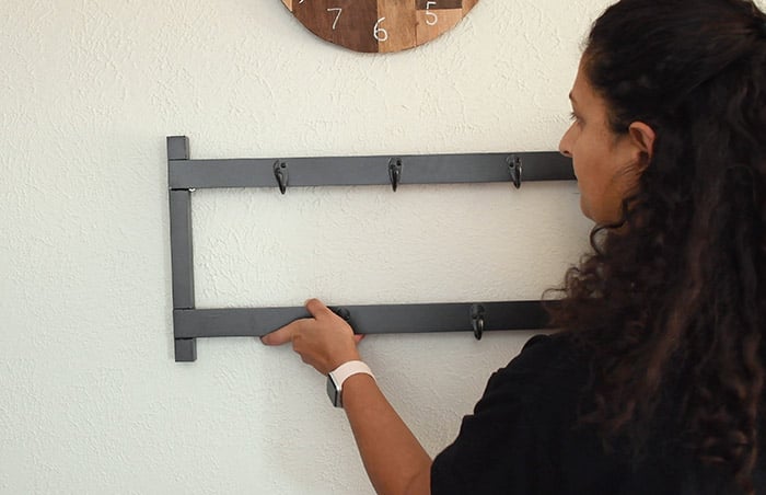 woman hanging up the metal coat rack