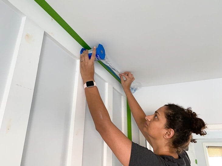 applying painter's plastic to prepare to paint a DIY board and batten wall